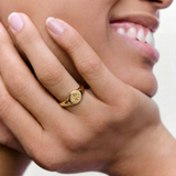 close up of a model wearing a gold signet ring with a star engraving on the top, crafted from gold-plated metal.