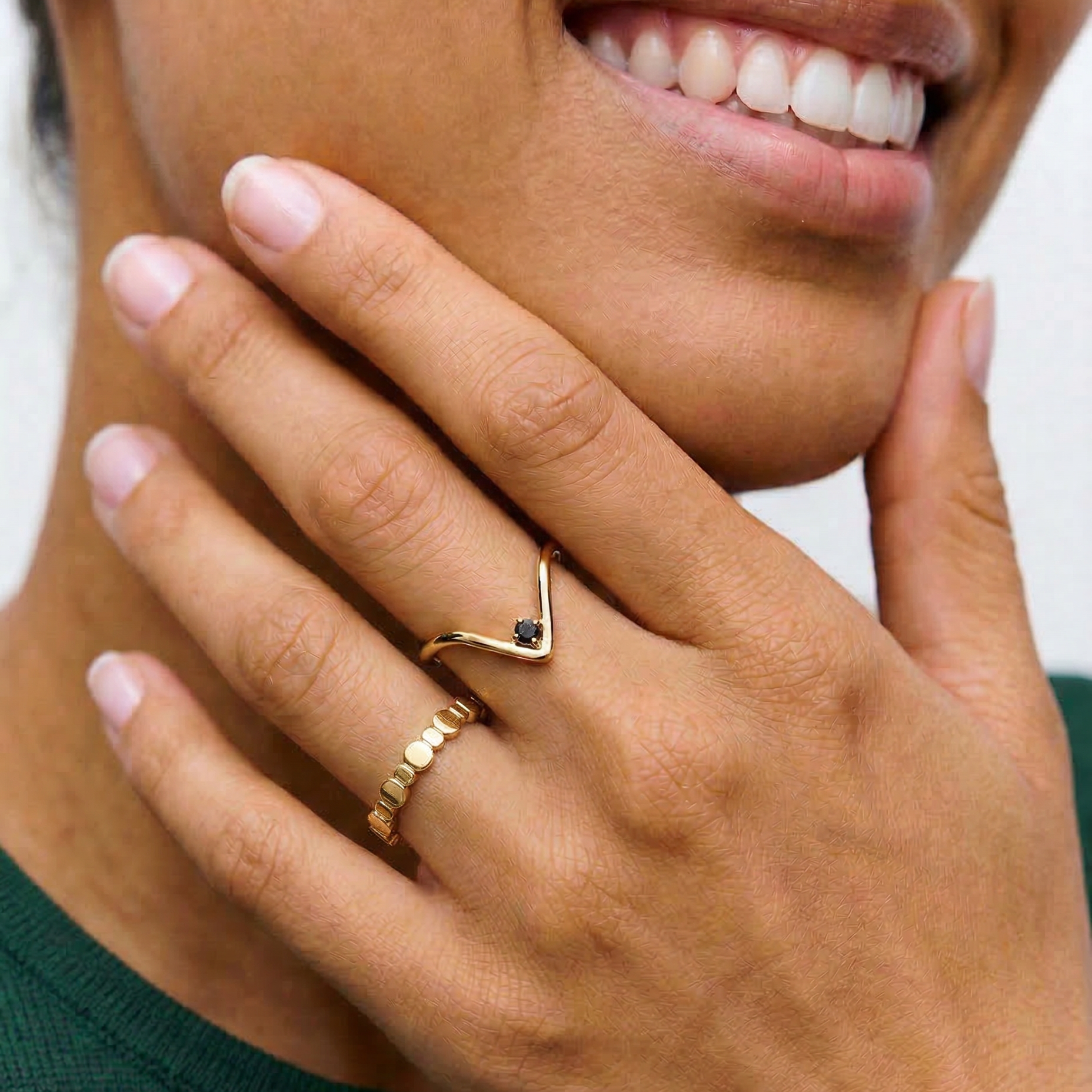 model wearing A gold-plated ring with an angular design and a black crystal set in a V-formation on a white background.