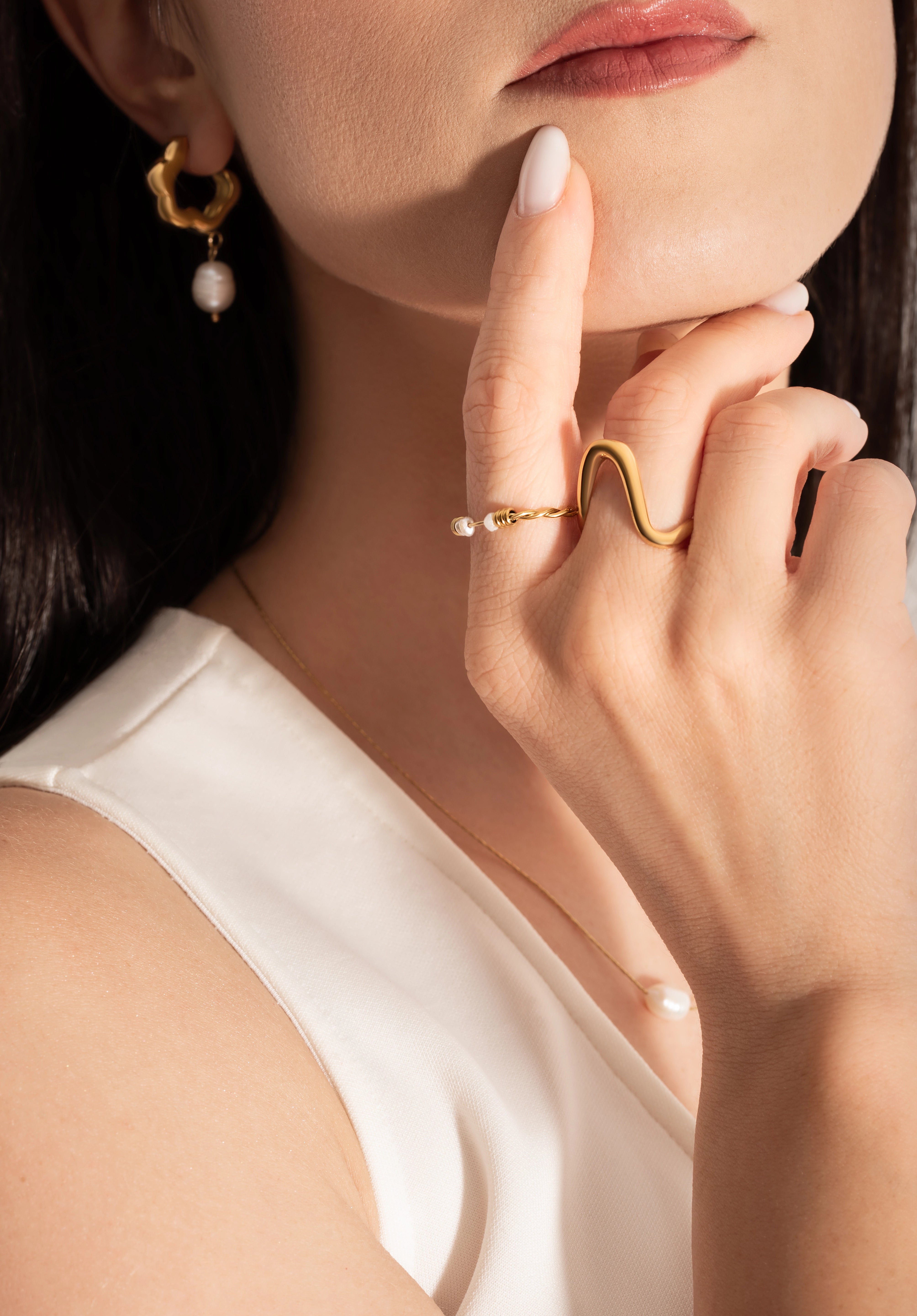 close up of a model wearing intertwined delicate gold plated ring with natural freshwater pearls