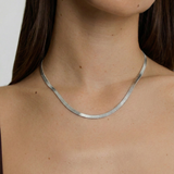 model wearing a sleek sterling silver herringbone chain necklace with an adjustable length and a heart charm