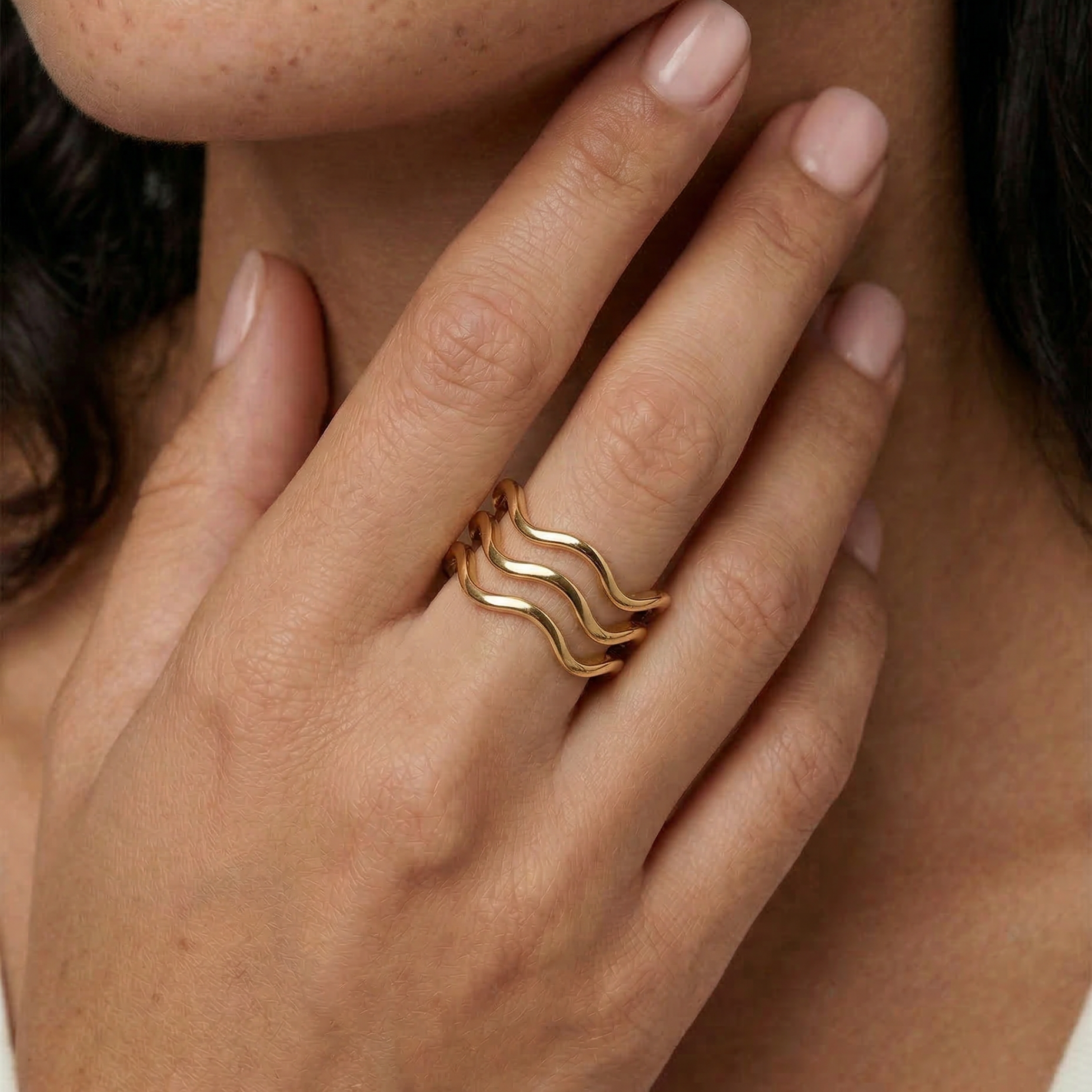 model wearing a gold-plated ring with a wave design open band