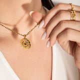 model wearing A gold-plated curb chain necklace with a round zodiac wheel pendant featuring multicolored sparkling crystals and a central moonstone.