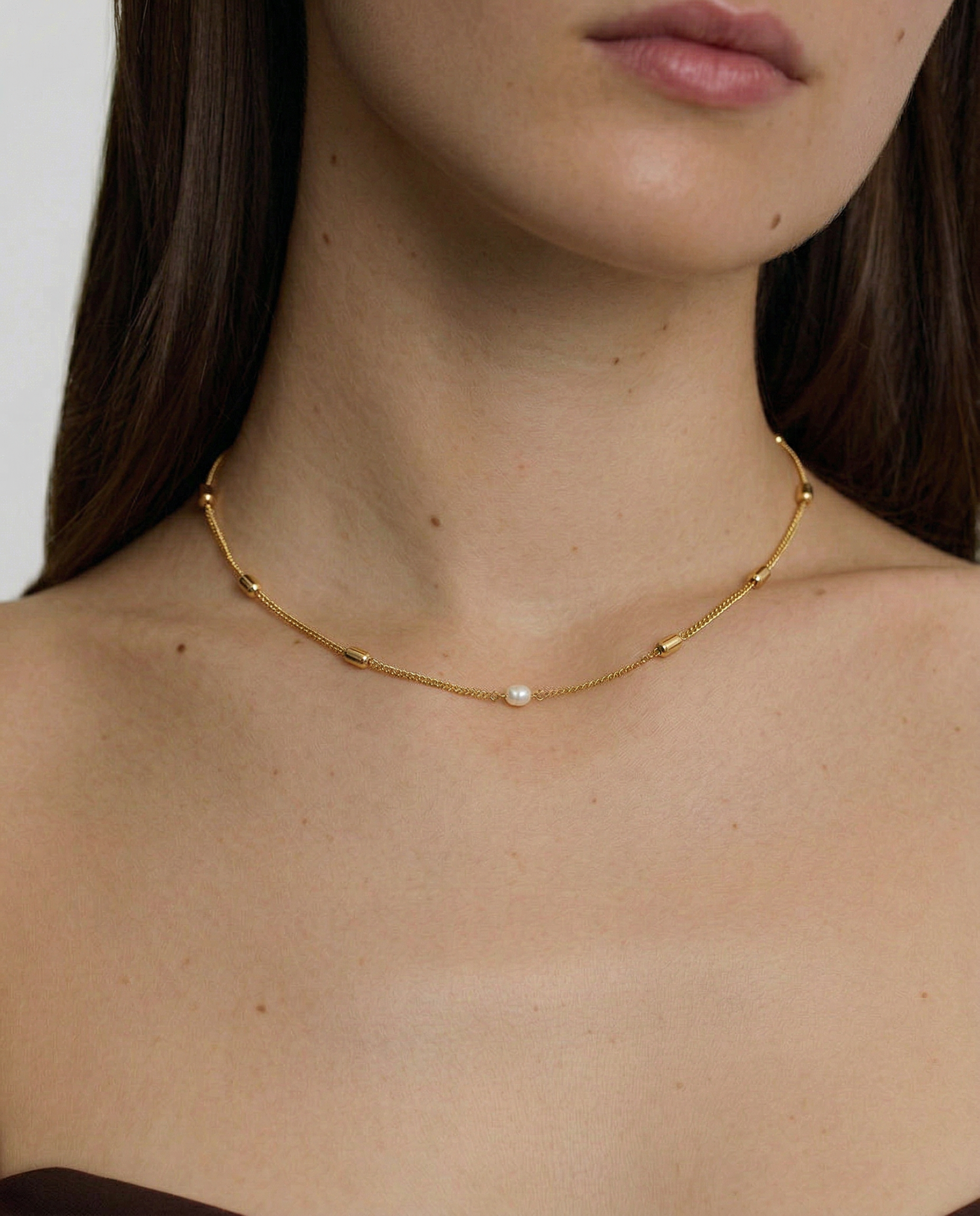 model wearing a delicate pearl necklace with gold plated accents