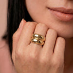 Close-up of a person wearing a gold-plated ring with a smooth, curved design 