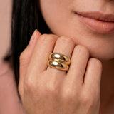 Close-up of a person wearing a gold-plated ring with a smooth, curved design 