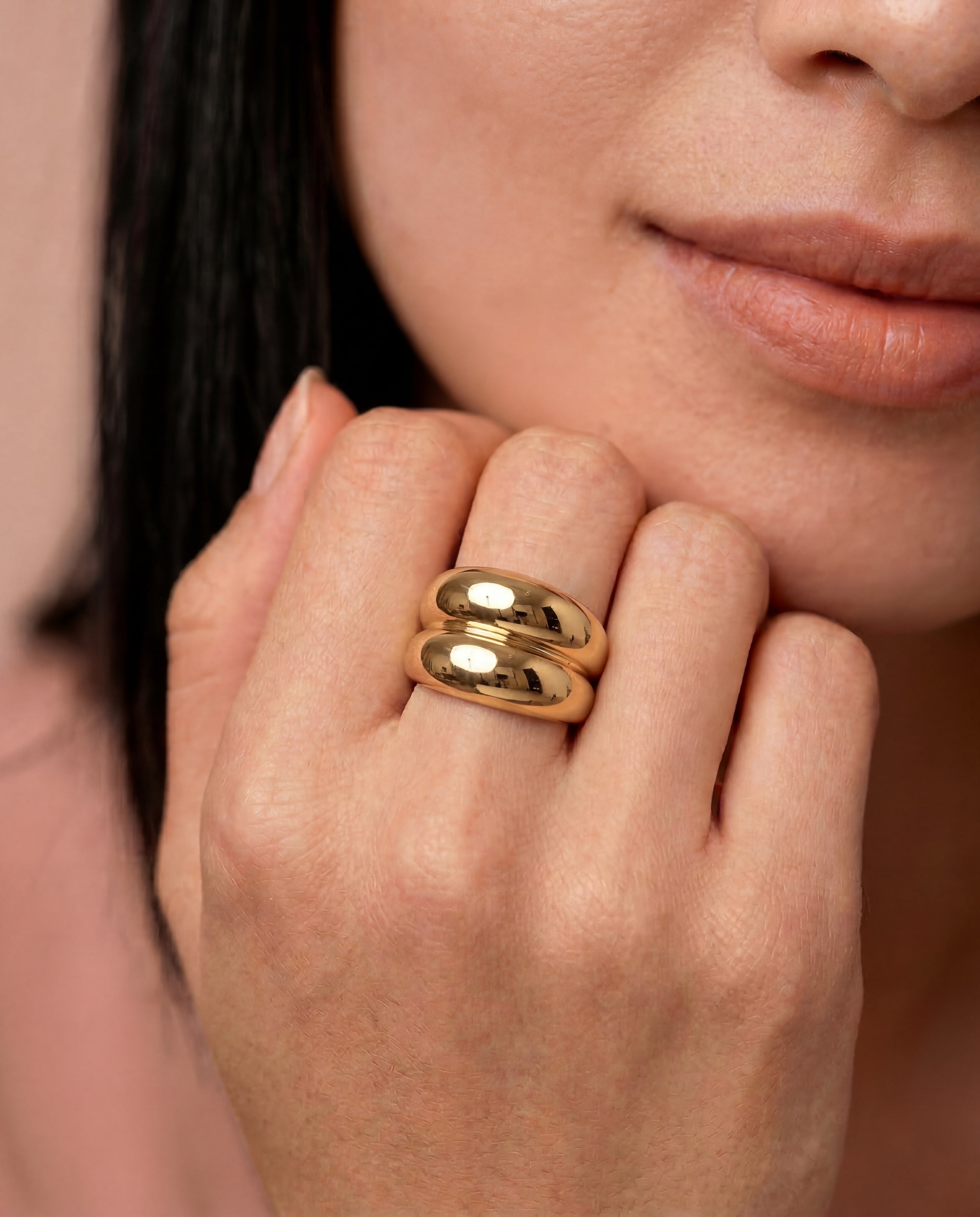 Close-up of a person wearing a gold-plated ring with a smooth, curved design 