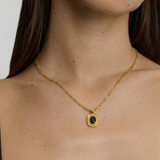 model wearing an 18k gold-plated stainless steel necklace with a polished Figaro chain and an oval medallion pendant featuring a deep black onyx stone