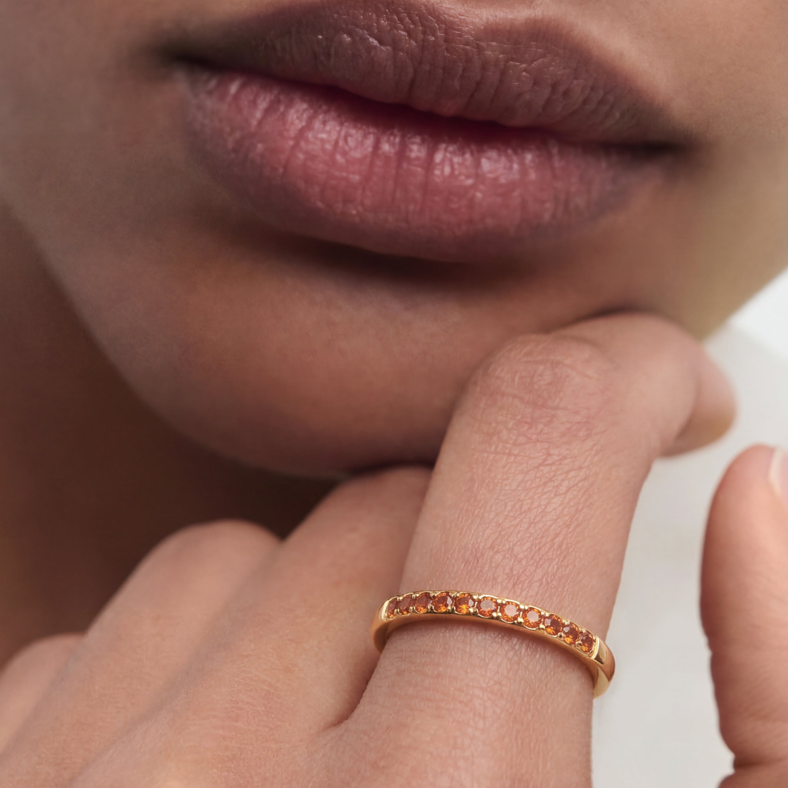 Close-up of a person wearing a gold ring on their finger with a neutral background