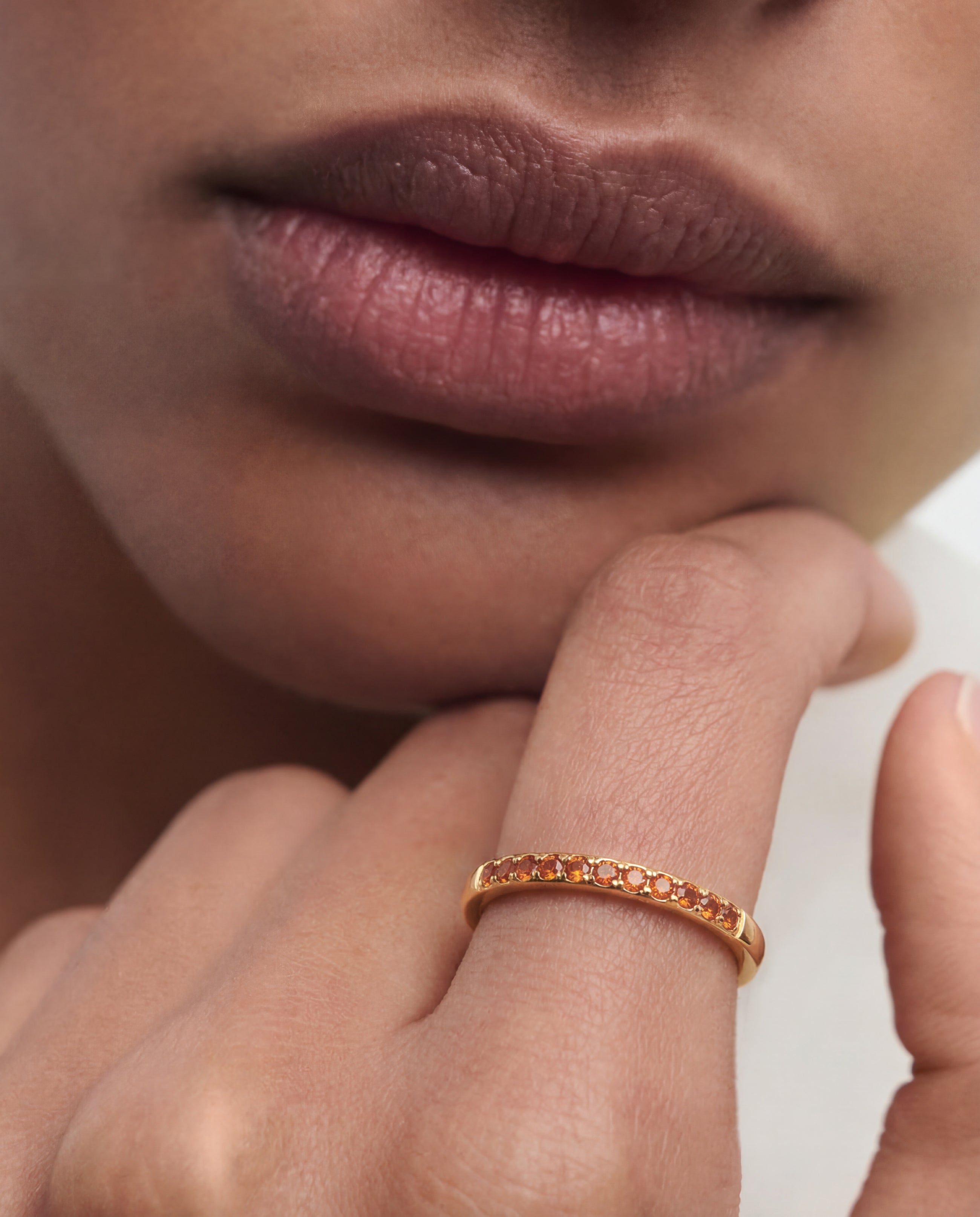 Close-up of a person wearing a gold ring on their finger with a neutral background