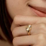 close up of a model wearing a gold-plated signet ring with an oval face featuring a sunburst pattern