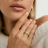 close up of a model wearing a gold-plated band ring with a ribbed texture