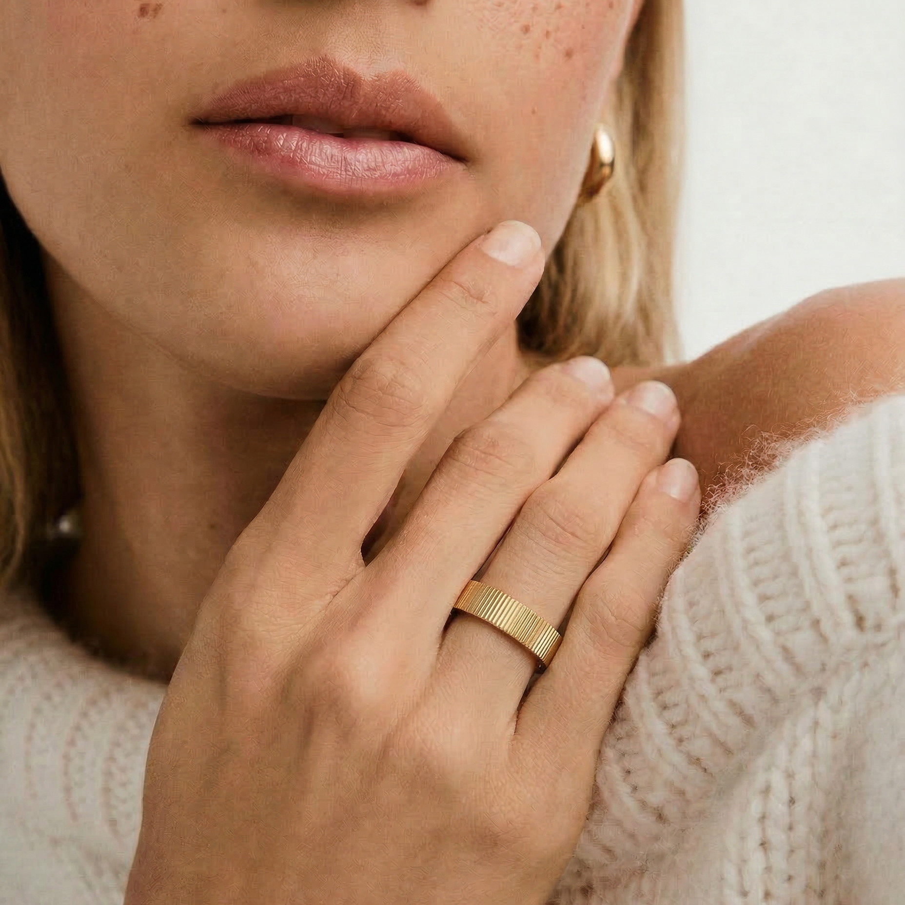close up of a model wearing a gold-plated band ring with a ribbed texture