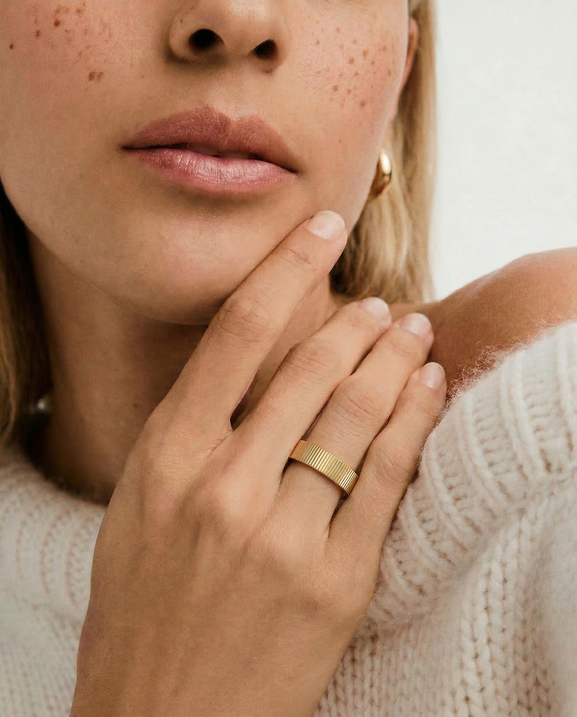 close up of a model wearing a gold-plated band ring with a ribbed texture