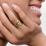 model wearing a gold-plated stainless steel ring with an architectural, coiled design