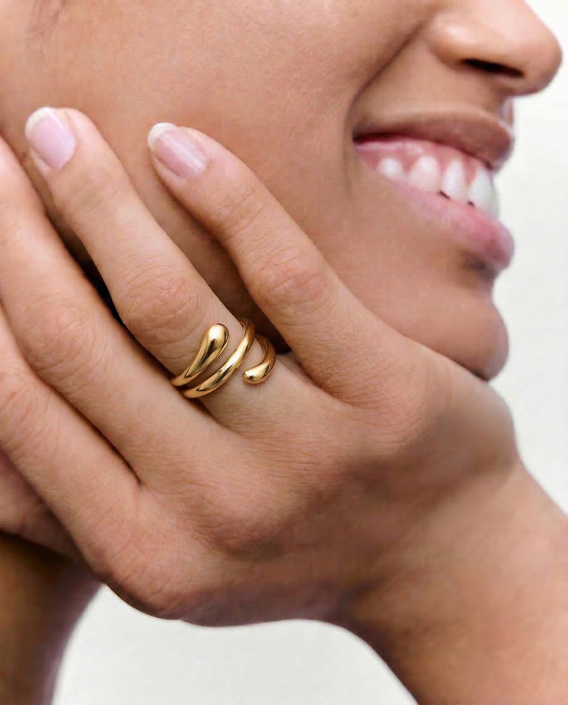 model wearing a gold-plated stainless steel ring with an architectural, coiled design