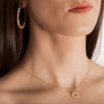 model wearing A gold necklace with a minimalist sun charm pendant