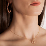 model wearing A gold necklace with a minimalist sun charm pendant