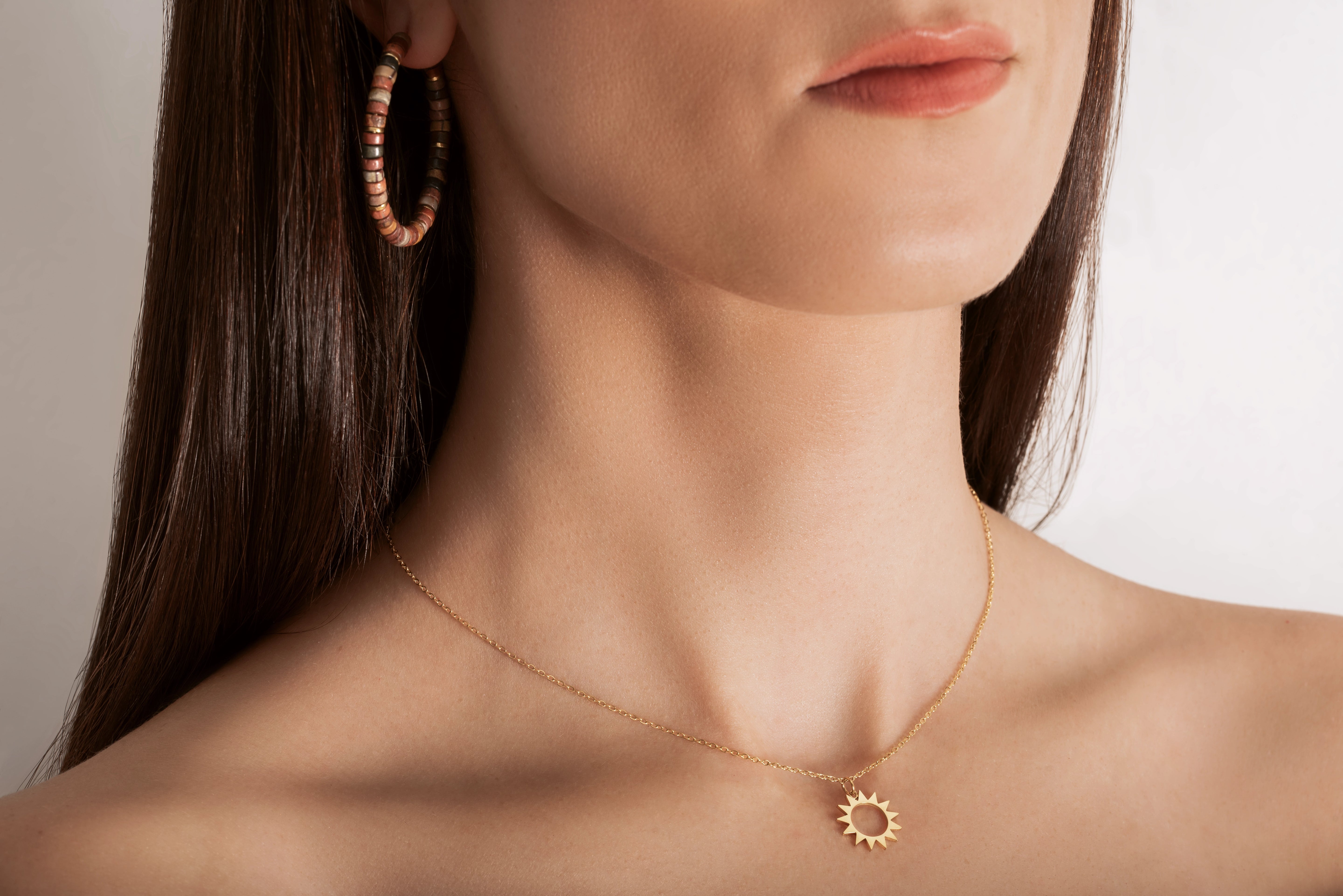 model wearing A gold necklace with a minimalist sun charm pendant