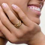 Close-up of a hand wearing a gold ring with a blurred background