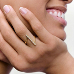 model wearing a contemporary gold-plated ring with an asymmetric design featuring a sleek bar adorned with a line of sparkling stones