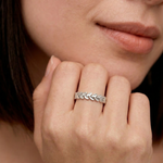 closeup shot of a model wearing a sterling silver laurel leaf band ring with a polished finish, featuring a series of leaves encircling the finger.