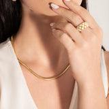 model wearing a big statement checkers board ring  and a snake chain necklace