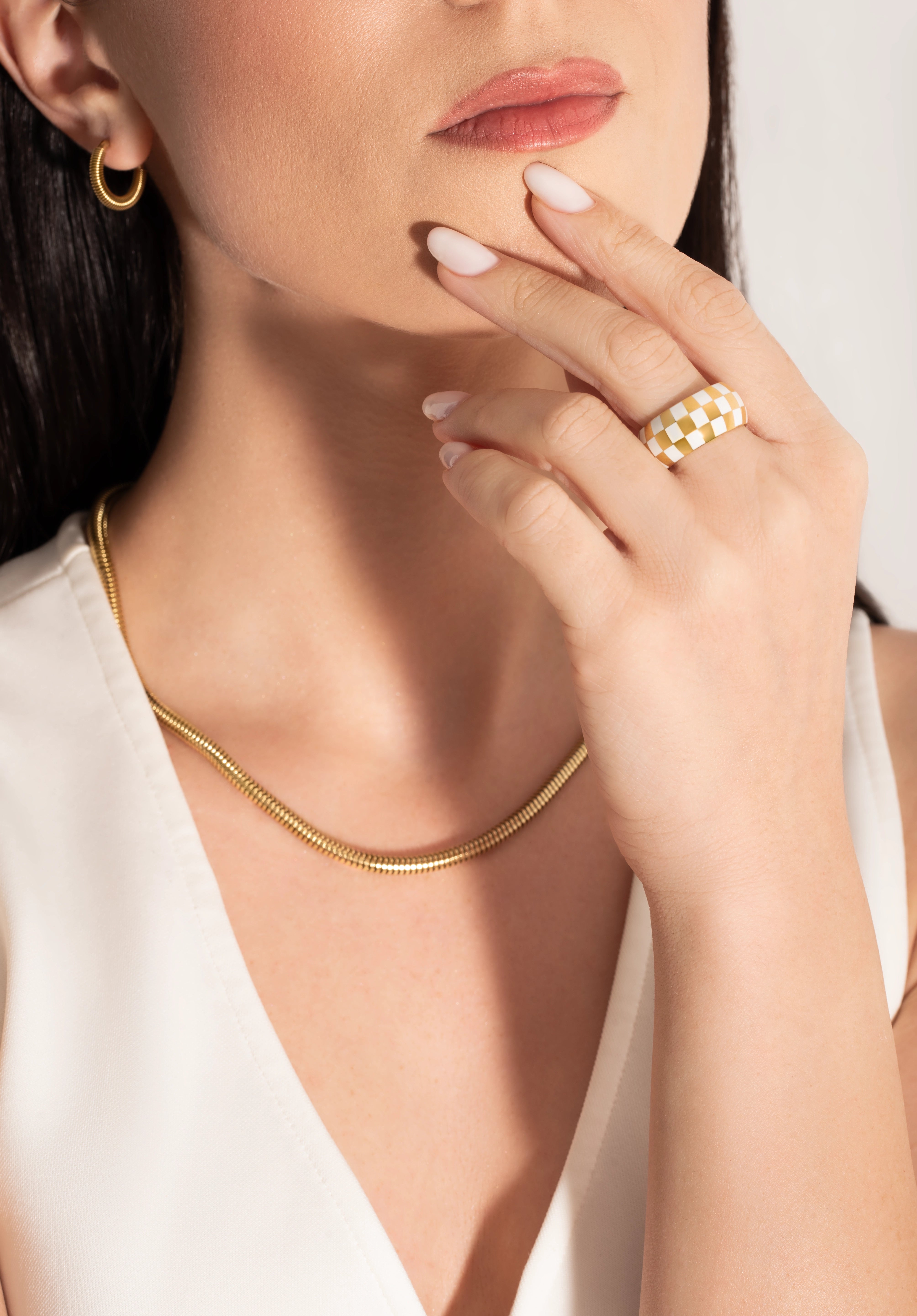 model wearing a big statement checkers board ring  and a snake chain necklace