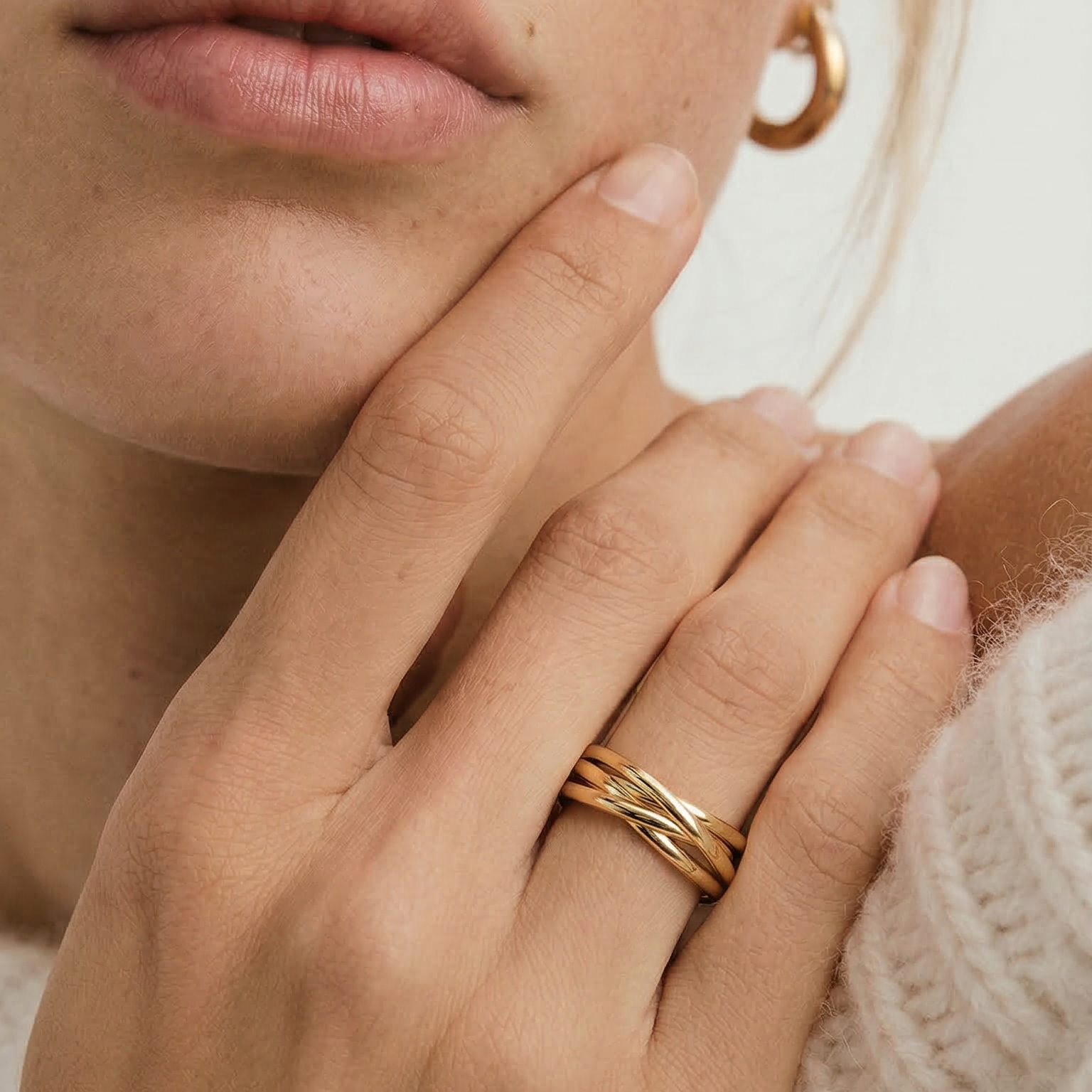 Close-up of a person wearing a gold ring on a neutral background
