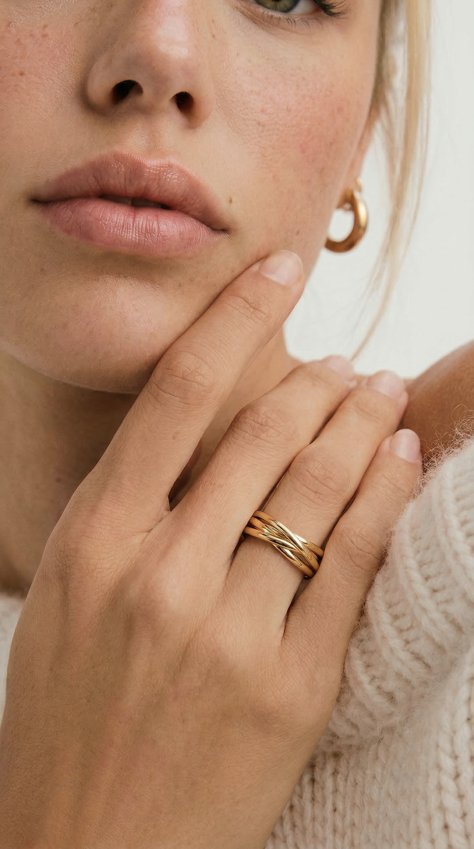 Close-up of a person wearing a gold ring on a neutral background