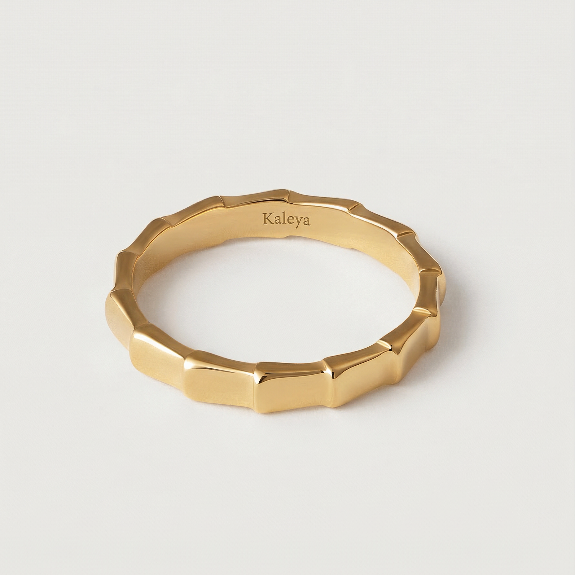 A gold-plated ring with a textured surface designed to mimic bamboo segments, displayed against a white background.