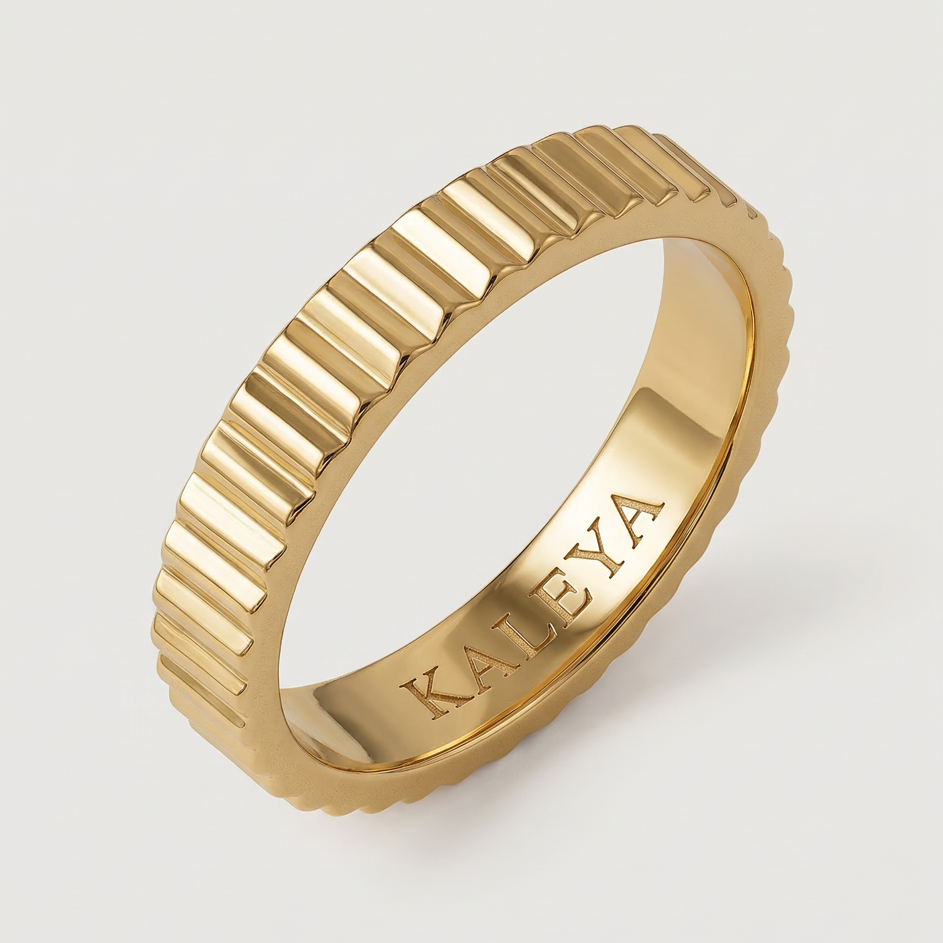 A gold-plated band ring with fluted edges, displayed against a white background