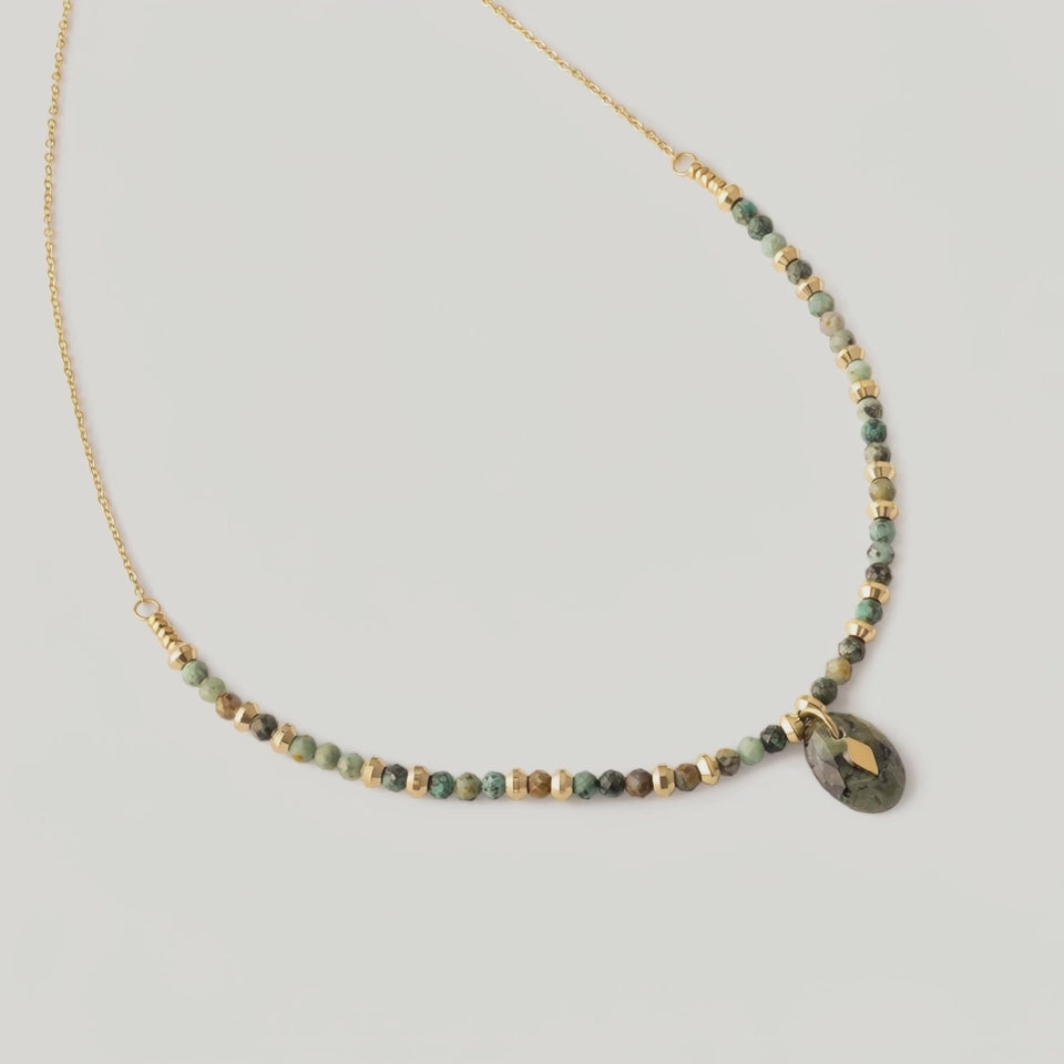 video of a gold-toned necklace with natural African turquoise beads in shades of sage, moss, and earth tones, featuring a smooth oval pendant.