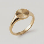 a video of a gold-plated signet ring with an oval face featuring a sunburst pattern