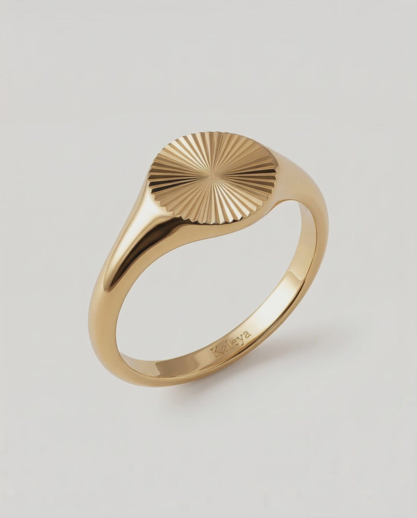 a video of a gold-plated signet ring with an oval face featuring a sunburst pattern