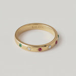 rotating video of a gold-plated ring with a series of vibrant gemstones set in star-shaped bezels along the polished band