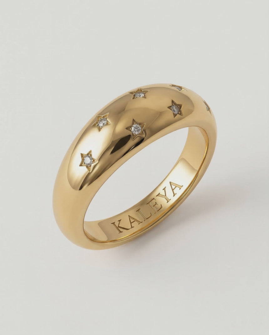 video showing a gold-plated ring with a smooth, domed surface adorned with five star-shaped bezels containing crystals