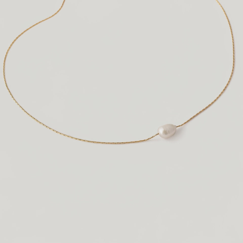 video of a single white pearl pendant on a thin gold chain