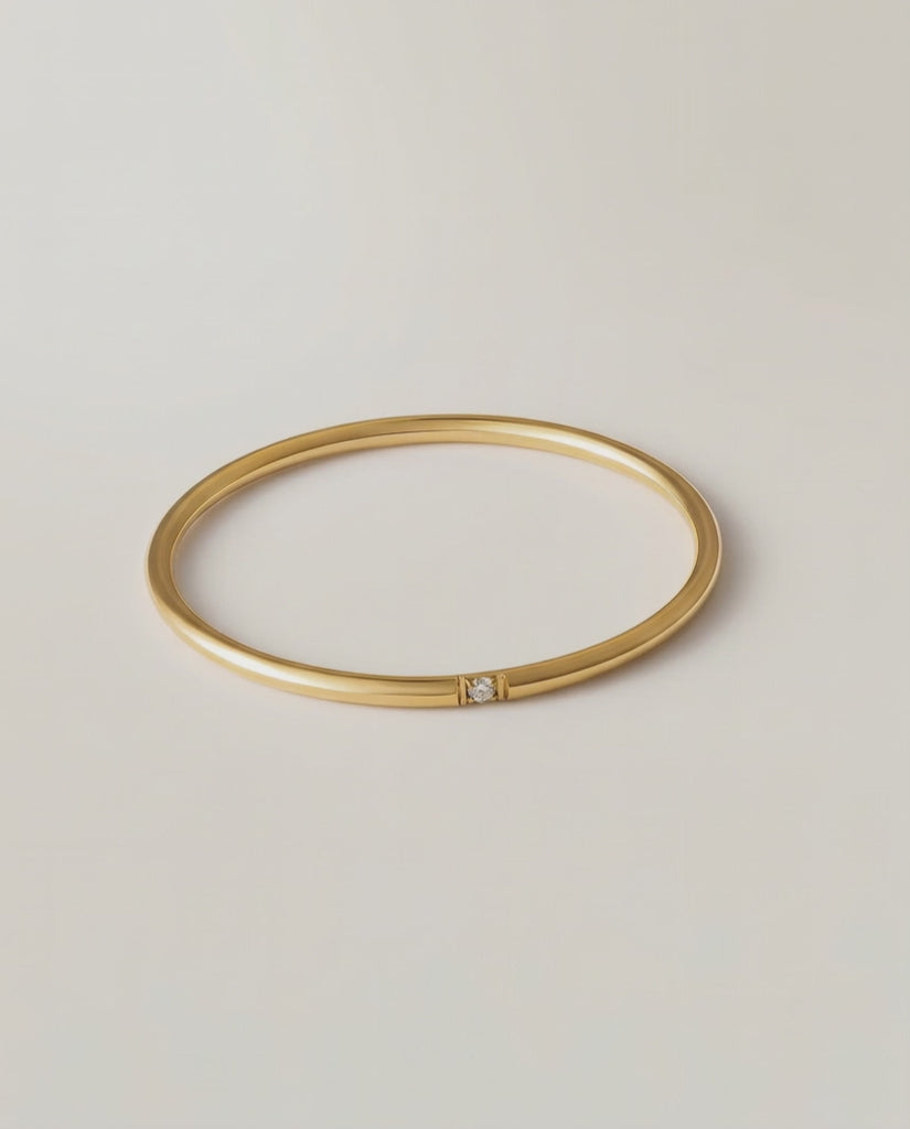 360 rotating video of a gold-colored band ring with a single sparkling stone on a white background.