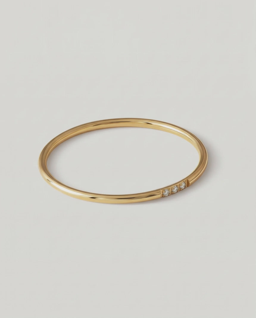 rotating video A gold-plated ring with a polished surface and a trio of brilliant cut cubic zirconia stones on one side