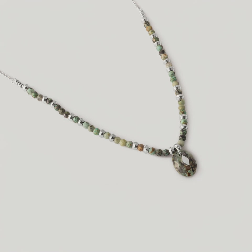 video of a necklace with variegated African turquoise beads and silver spacers, ending in a teardrop-shaped pendant