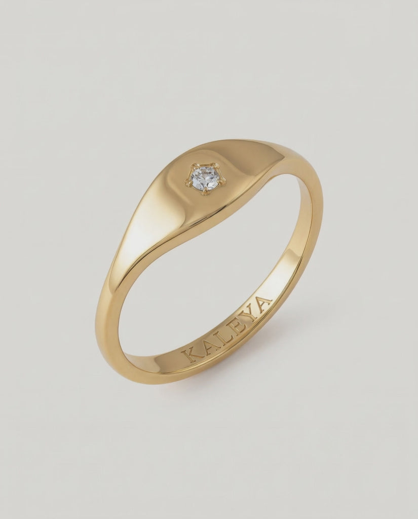 360 video of a gold signet ring with a small star-set crystal on the top, displayed against a white background.