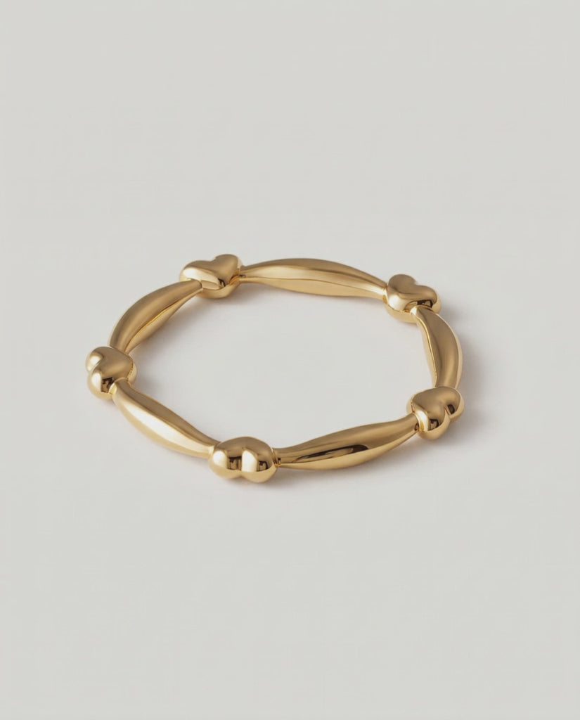 rotating video of a gold-plated ring with heart-shaped links and elongated bars creating a chain-like design