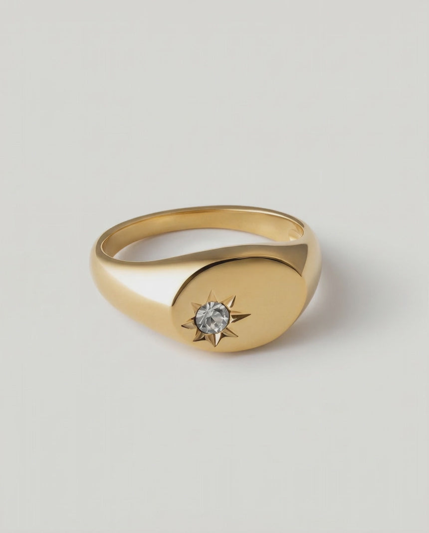 rotating video of a gold-plated signet ring with an oval face featuring a dazzling stone set in a starburst pattern