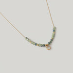 video of a gold-plated necklace with sage-green faceted crystals and a gold spacer bead chain, ending in a cubic zirconia charm.