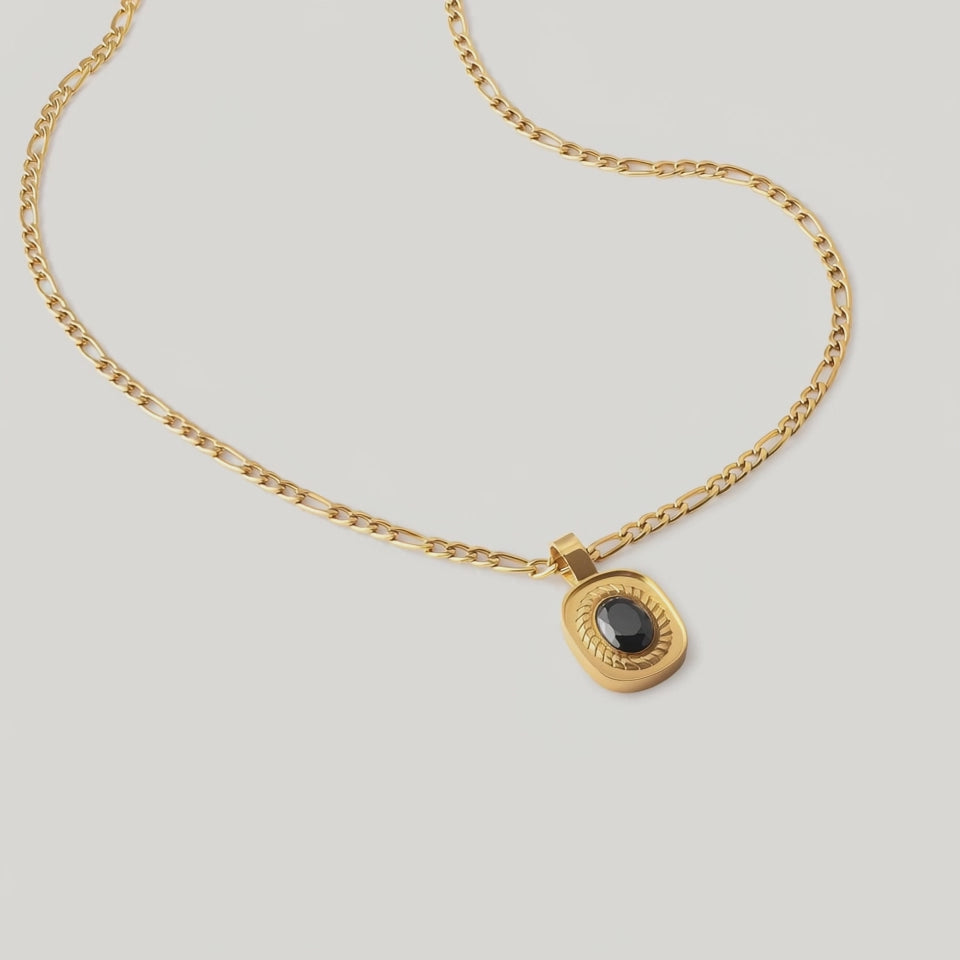 video of an 18k gold-plated stainless steel necklace with a polished Figaro chain and an oval medallion pendant featuring a deep black onyx stone