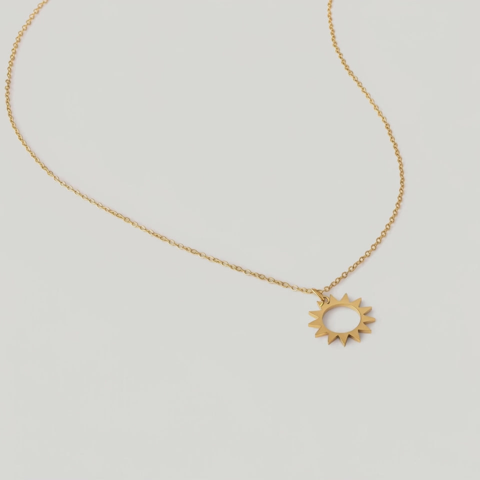 video of a gold necklace with a minimalist sun charm pendant