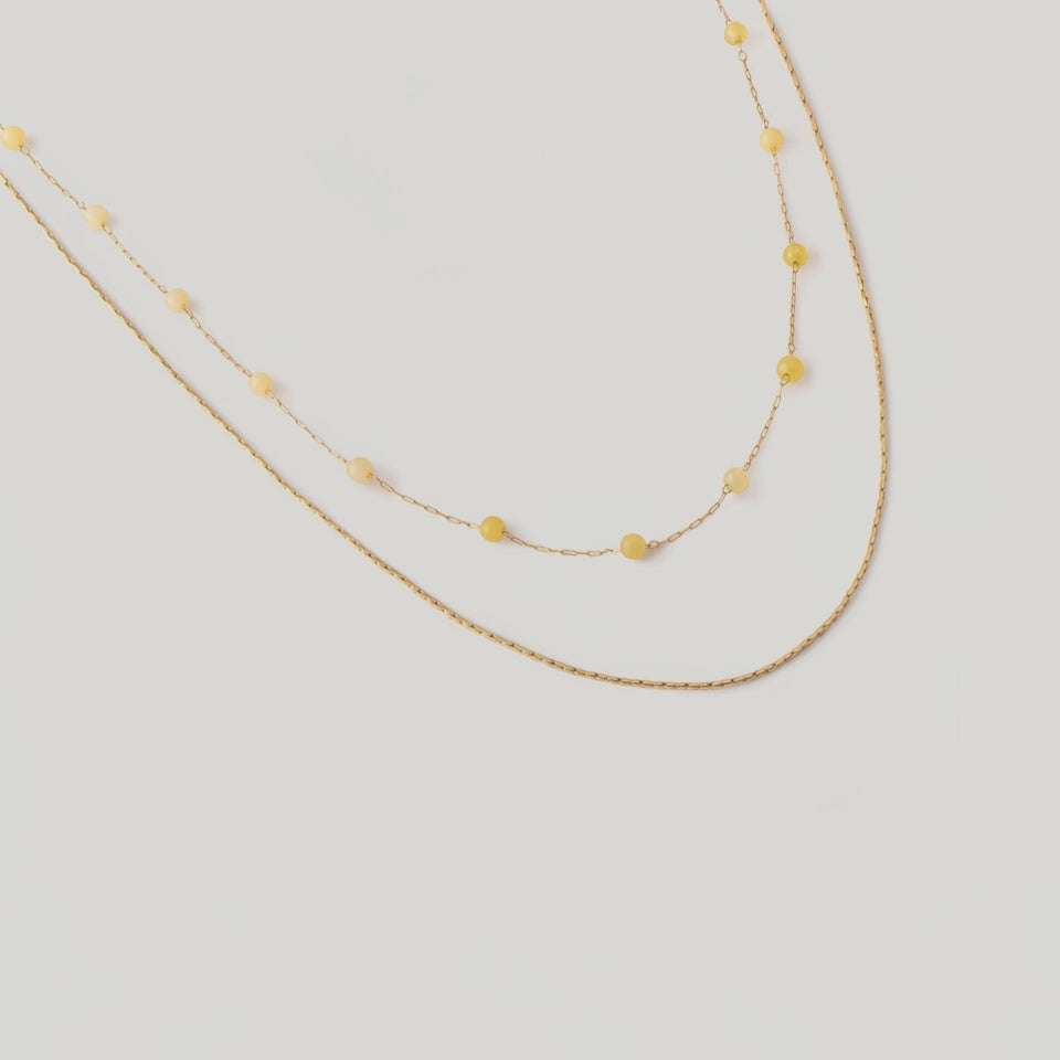 video of a two-tone necklace with gold links and yellow stones