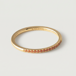 a gold-plated ring with a single row of orange crystals around its circumference.