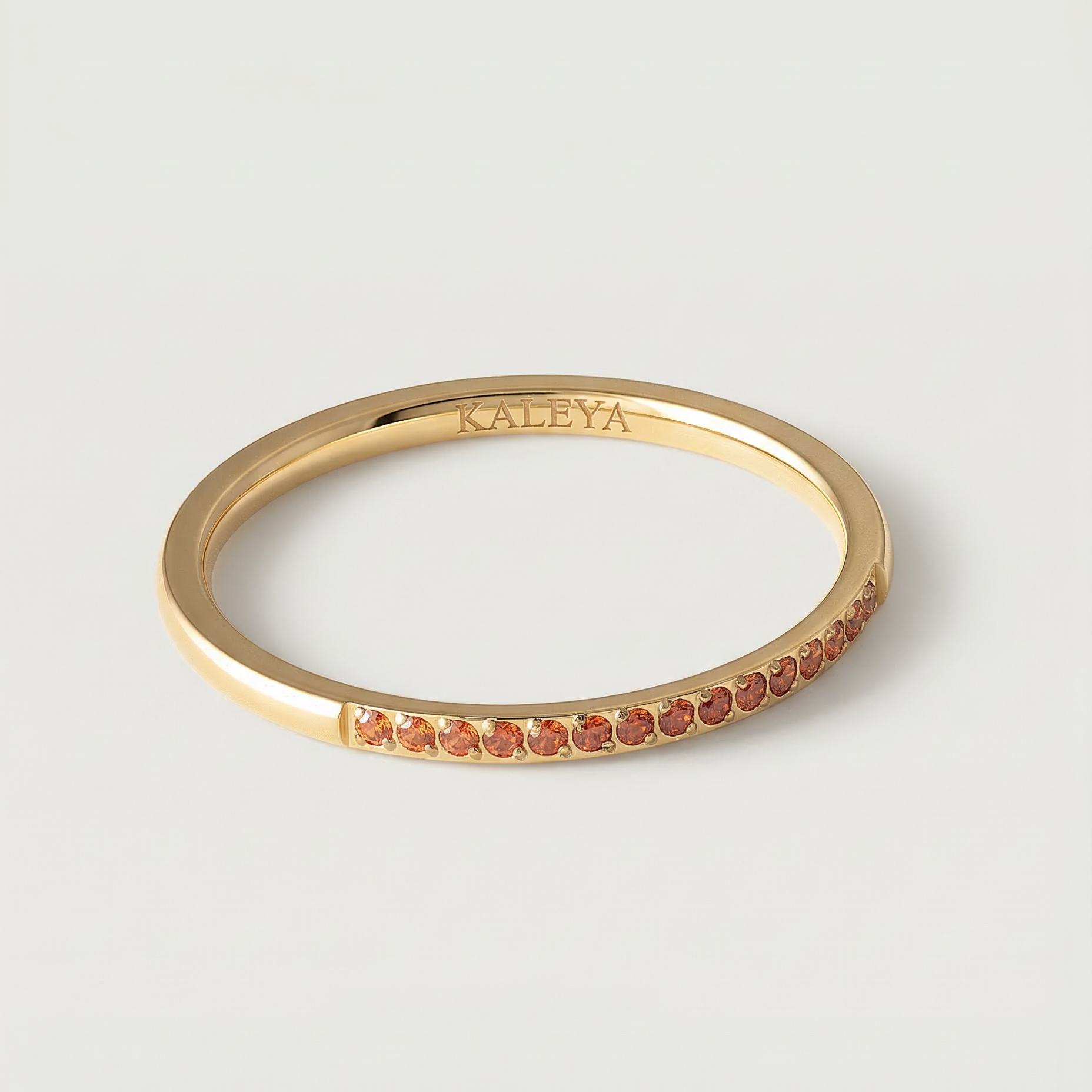 a gold-plated ring with a single row of orange crystals around its circumference.