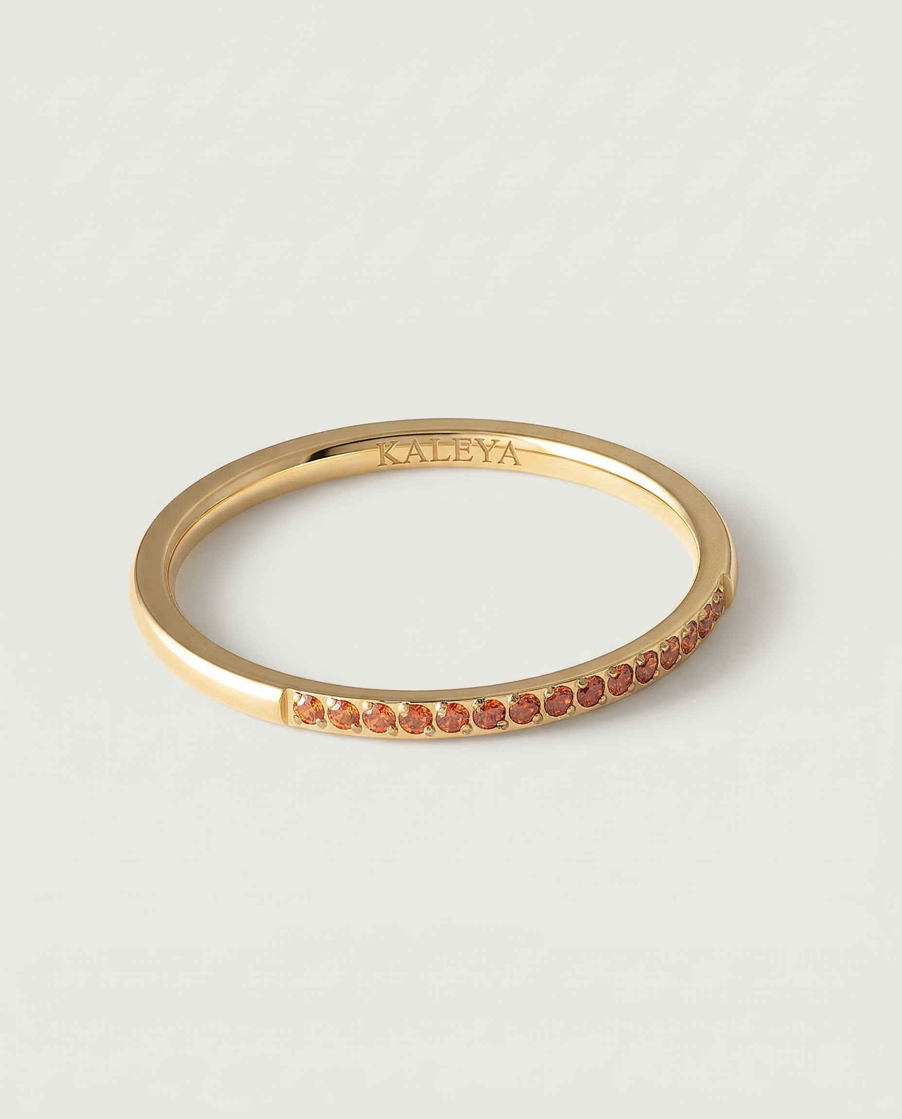 a gold-plated ring with a single row of orange crystals around its circumference.
